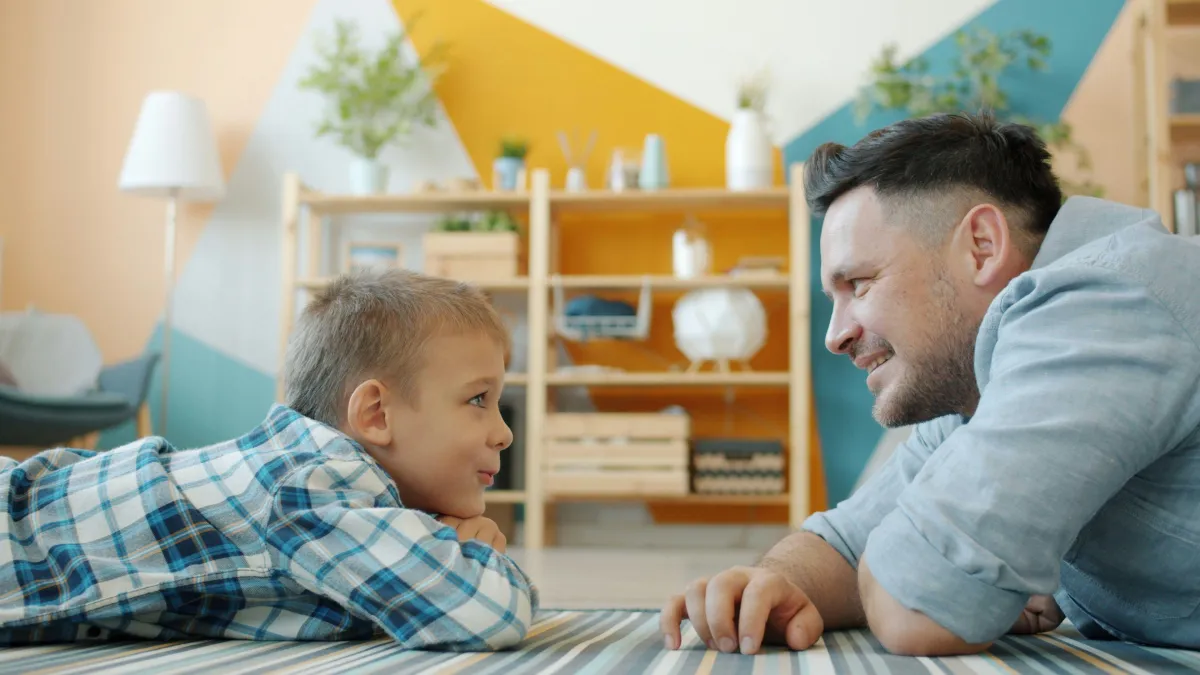 Dad and son laying on floor looking at each other